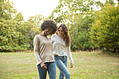 Lächelnde junge Freundinnen gehen im Park spazieren