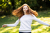 Porträt einer lächelnden jungen Frau, die sich im Park umdreht