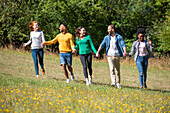 Glückliche junge Freunde, die zusammen in einem öffentlichen Park spazieren gehen