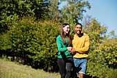 Lächelndes junges Paar beim Spaziergang im öffentlichen Park