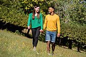 Smiling young couple walking in public park