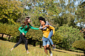 Lächelnde junge Freunde haben Spaß beim Spazierengehen in einem öffentlichen Park