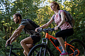 Young couple cycling bicycle in forest