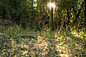 Junger Mann trägt Fahrrad beim Spaziergang im Wald