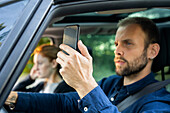 Young man using smart phone while driving a car