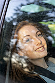 Lächelnde junge Frau im Auto sitzend