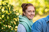 Portrait of smiling young woman sitting in public park
