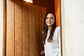 Porträt einer lächelnden jungen Frau, die in der Nähe der Tür steht