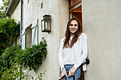 Portrait of smiling young woman standing at doorstep