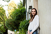 Portrait of smiling young woman standing near door