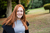 Portrait of smiling young woman sitting in public park