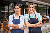 Mittelaufnahme von zwei weiblichen Restaurantbesitzern, die vor ihrem Geschäft posieren