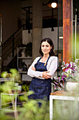 Plant nursery female owner leaning on entrance with arms crossed