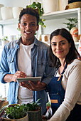 Plant nursery owners looking at the camera while holding digital tablet