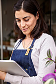 Garden center female owner using digital tablet