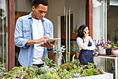 Latin American male worker taking inventory of plants in nursery