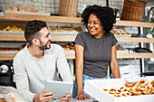 Bakery coworkers looking at each other while standing behind counter