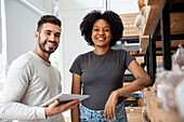 Male and female entrepreneur taking inventory while looking at the camera