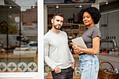 African American female bakery owner standing with colleague at doorway