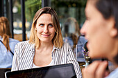 Front view of female entrepreneur working with her Latin-American partner seen out of focus from behind