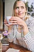 Mittelaufnahme einer attraktiven Frau, die in einem Café eine Tasse Kaffee genießt