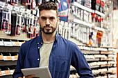 Hardware shop owner looking at the camera while holding digital tablet