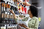 African American Female hardware shop owner checking tools hanging on rack