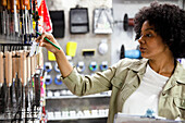 African American female hardware shop worker taking notes of products on clipboard