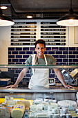 Latin American young man looking at the camera while standing behind counter