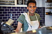 Smiling Latin American grocery store worker standing behind counter