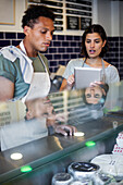 Grocery store coworkers discussing over digital tablet