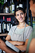 Confident female wine store worker discussing with coworker