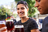 Portrait of happy young Latin-American woman smiling at camera while holding a glass of beer