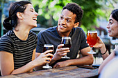 Young Latin American man drinking beer with female friends