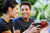 Junge erwachsene Frau und Freunde stoßen mit Bier an