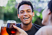 Lateinamerikanischer junger Mann, der in die Kamera schaut, während er mit Freunden Bier trinkt