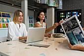Two young female home decor entrepreneurs sitting at their desk with a client