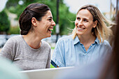 Female coworkers laughing while sitting outdoors