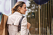 Seitenaufnahme einer Frau, die beim Schaufensterbummel Taschen trägt