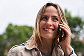 Close-up shot of smiling woman speaking on cell phone in the street