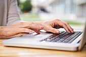 Close-up shot of woman's hands typing on a laptop computer