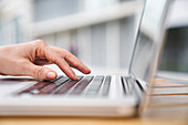Close-up side view shot of woman's hand typing on a laptop computer
