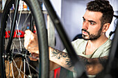 Junger erwachsener männlicher Mechaniker, der ein Fahrrad in der Werkstatt repariert