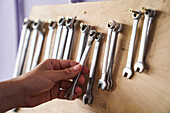 Close-up shot of hand taking a combination spanner from a wall rack
