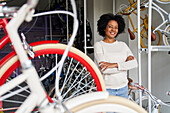 Medium shot of female African American bicycle shop owner in her store with bicycles in the foreground