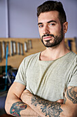 Medium-shot portrait of bearded shop owner standing in his workshop in front of his tools
