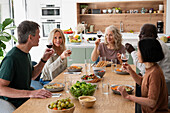 Mittlere Aufnahme einer Gruppe von Mitarbeitern, die beim Mittagessen zu Hause einen Toast aussprechen