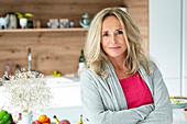 Portrait of middle-aged woman looking at camera standing in kitchen