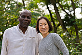 Portrait of middle-age African American man and Asian American woman outdoors in public park