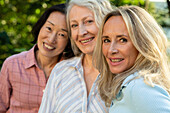 Drei ältere Frauen posieren zusammen für ein Gruppenfoto im Freien